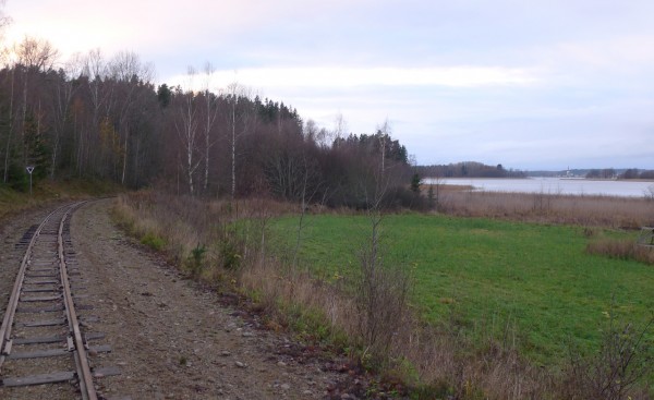 Syltaberg österifrån. Skärningen finns där skogskanten viker ner mitt i bild. Mariefred med kyrkan skymtar på andra sidan Gripsholmsviken till höger i bild.
